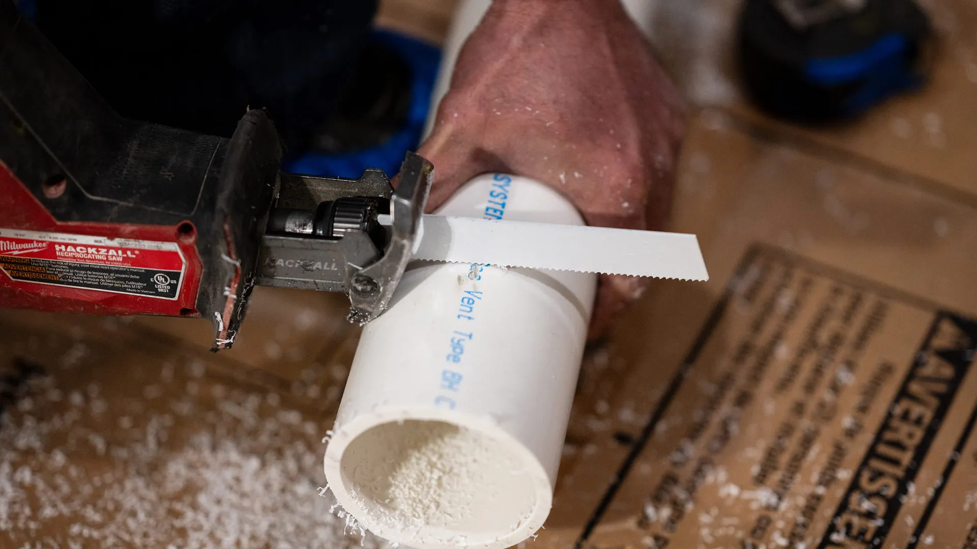 Plumber-Cutting-White-PVC-Pipe-With-Power-Saw