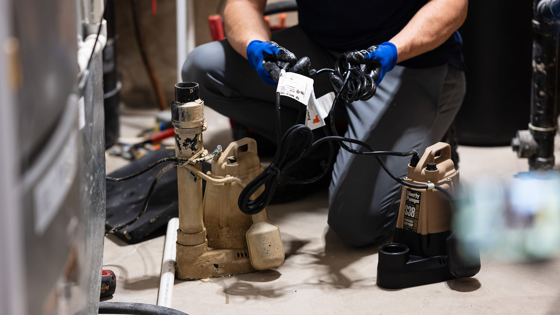 Technician-Comparing-Old-Sump-Pump-With-New-Liberty-Pump