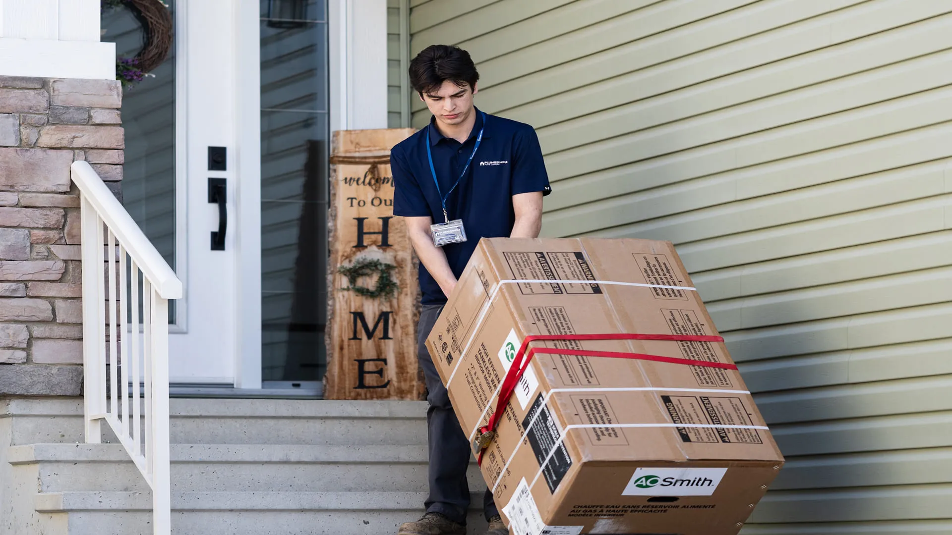 Technician-Moving-Water-Heater-Box-Up-Front-Steps