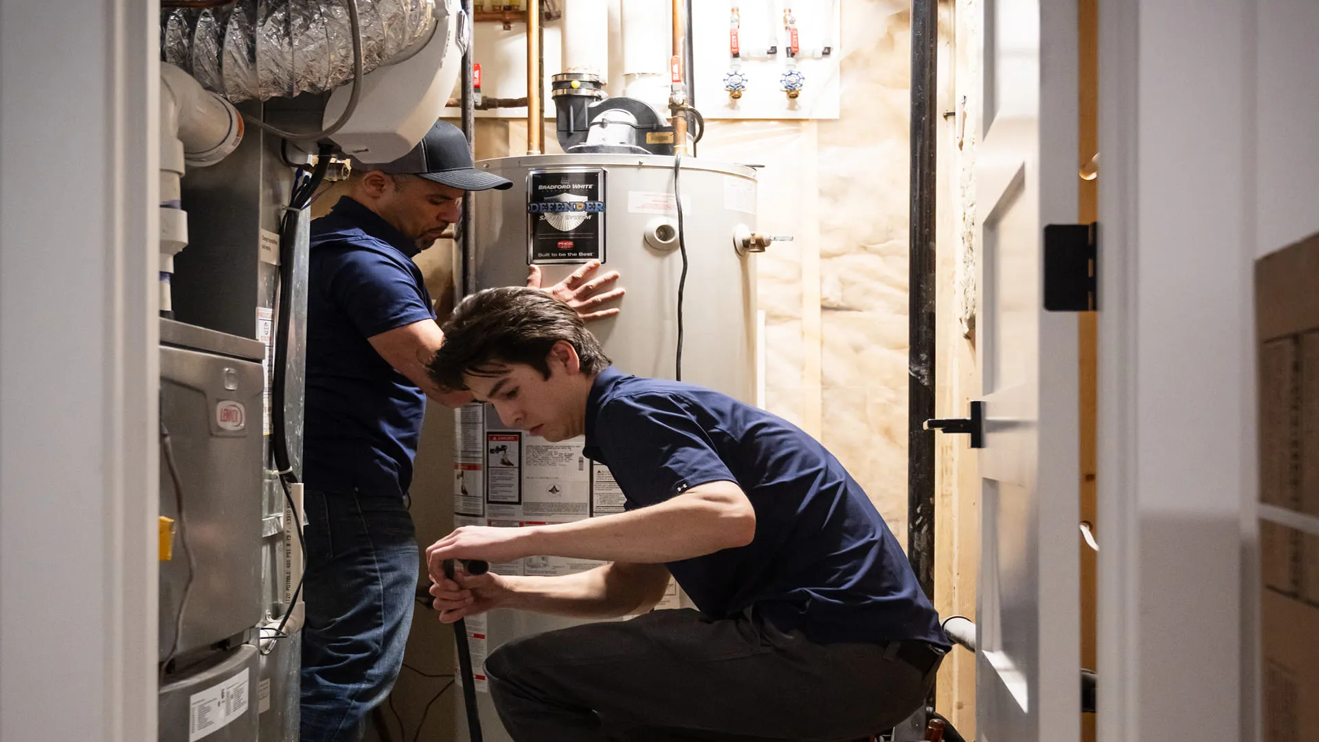 Technicians-Servicing-Water-Heater-In-Utility-Closet
